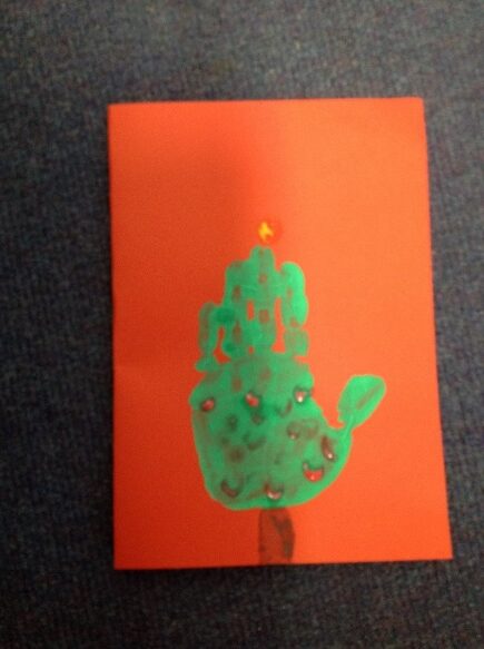 A green handprint on an orange paper Description automatically generated