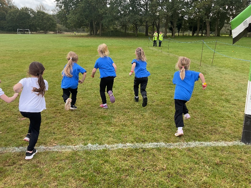 A group of young girls running on a field

Description automatically generated